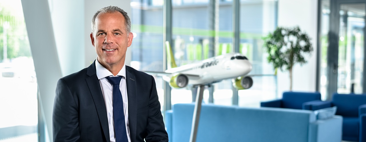 Photo of airBaltic CEO MArtinGauss sitting next to a model airplane in airBaltic livery